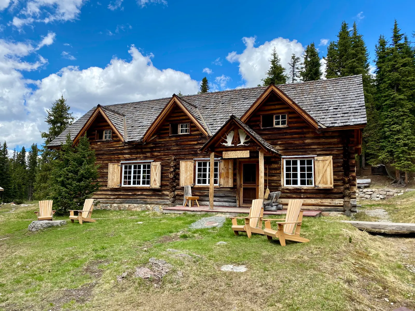 Skoki Lodge log buildings in a grassy backcountry clearing.